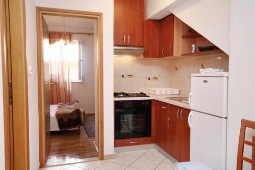 苏佩塔尔Apartments with a parking space Supetar, Brac - 6037的厨房配有木制橱柜和白色冰箱。