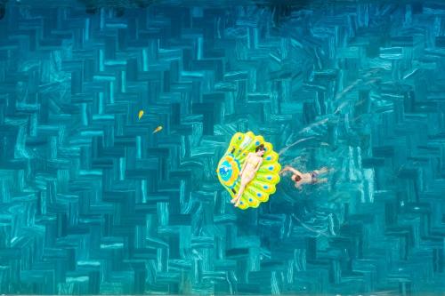 富国Mai Phuong Resort Phu Quoc的漂浮在游泳池冲浪板上的人