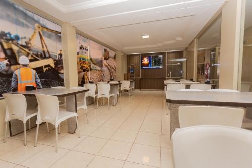 帕劳阿佩巴斯HOTEL EXECUTIVO的用餐室配有桌子和白色椅子