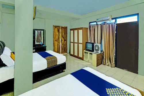 普兰巴南SPOT ON 91540 Ukuh Guesthouse的酒店客房设有两张床和电视。