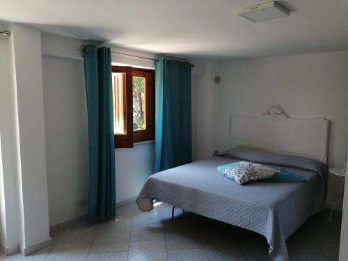 布泰拉Scrusciu do Mari的一间卧室配有一张带蓝色窗帘的床和一扇窗户