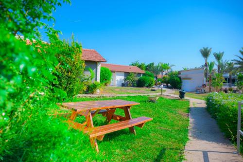 亚实基伦Agamim Hotel Ashkelon的一张木餐桌,坐在草地上