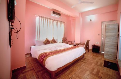 博卡拉Hotel Peace Stupa的卧室设有粉红色的墙壁和一张大床
