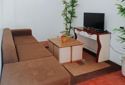 OraconRedDoorz @ Southern Suites Guimaras的客厅配有沙发和带电视的桌子