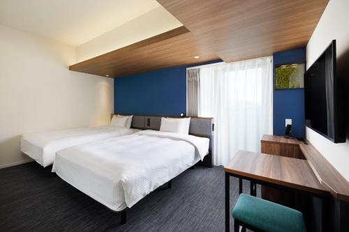 东京Prince Smart Inn Ebisu的酒店客房设有两张床和一台平面电视。
