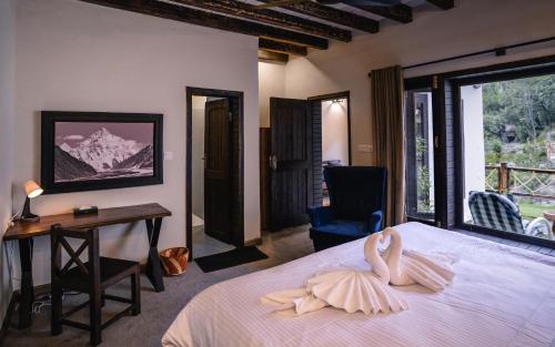 罕萨Offto Resort Hunza的一间卧室配有一张床、一张书桌和一个窗户。