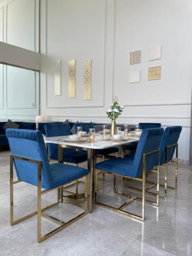阿可贺巴شاليه رويال الخبر - Royal Resort AL Khobar的一间带桌子和蓝色椅子的用餐室