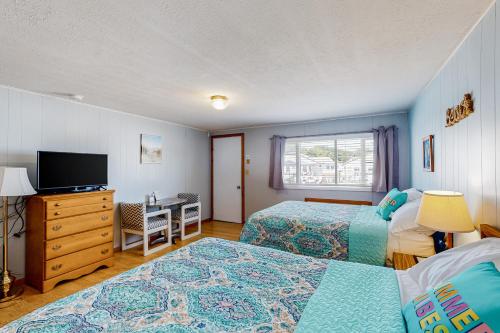 威尔斯Coastal Calm A的一间卧室配有两张床、一张桌子和一台电视。