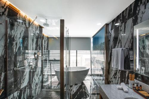 第比利斯Marjan Plaza Hotel的带浴缸和玻璃淋浴间的浴室