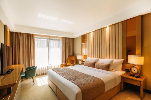 第比利斯Marjan Plaza Hotel的酒店客房设有一张大床和一台电视。