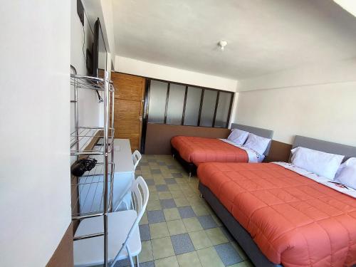库斯科Las Dalias的酒店客房配有两张床和一张书桌