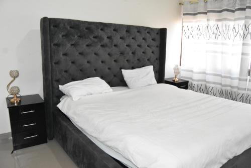 卢萨卡Specious Old Zamtel flats的一间卧室配有一张大床和黑色床头板