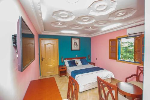 Assougoula EmoMont Bleu Hôtel的一间卧室配有一张床,另一间卧室配有桌子