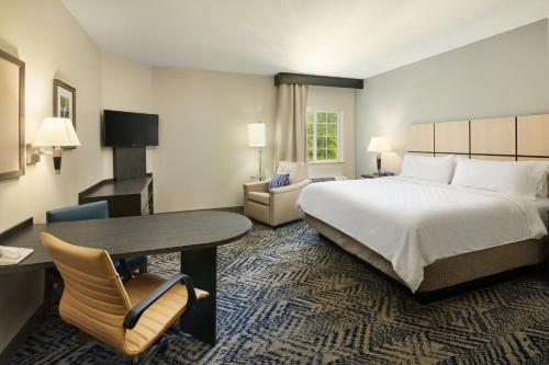 查尔斯顿Candlewood Suites Charleston-Northwoods, an IHG Hotel的酒店客房,配有一张床、一张桌子和椅子