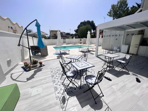 普尔萨诺B&B Alto Salento - Pool and Sun的游泳池旁带桌椅的天井
