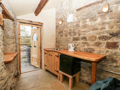 LydbrookTinmans Cottage的厨房设有木台和石墙