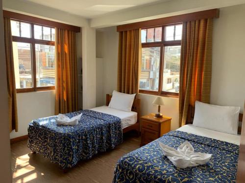 帕拉卡斯Hostal El Amigo的酒店客房带两张床和两个窗户