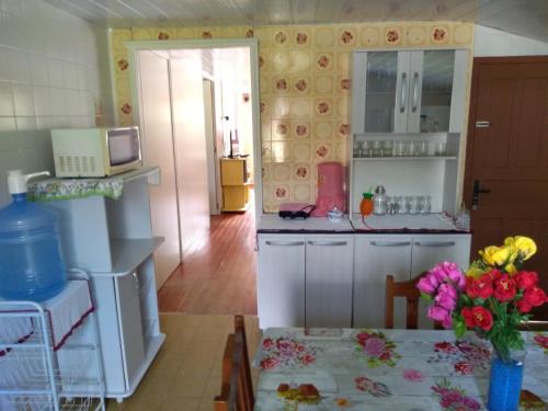 皮涅拉Casa na Pinheira, Praia de Cima的厨房配有冰箱和带鲜花的桌子