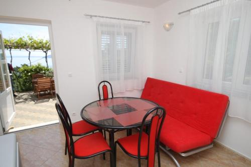 密德维亚Apartments with a parking space Medveja, Opatija - 7721的一间用餐室,配有红色的沙发和玻璃桌