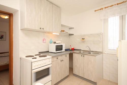 内里吉恩Holiday apartments Osor, Losinj - 8004的白色的厨房配有炉灶和微波炉。