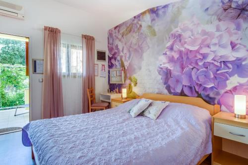康斯基Apartments by the sea Artatore, Losinj - 7952的卧室配有一张挂着花壁画的床。