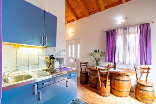 拉茨斯切Apartments by the sea Kneza, Korcula - 9168的厨房配有蓝色橱柜和酒桶桌子