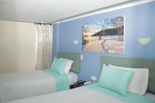 马尼萨莱斯Hotel Dubai的蓝色的客房设有两张床和窗户。