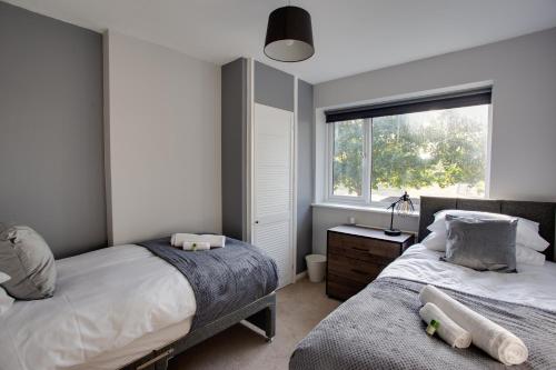 Sunbury CommonSAXON ROAD - A 3 Bedroom House with Garden by Prestigious Stays - Includes Wifi, Netflix & Amazon Alexa的一间卧室设有两张床和窗户。