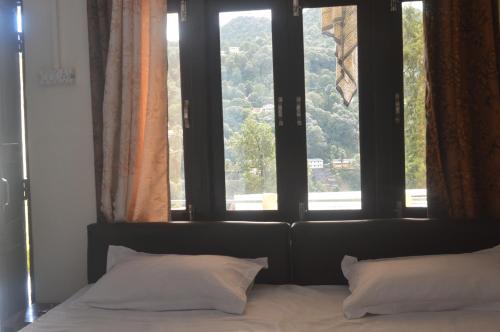 奈尼塔尔Lakshmi Kutteer Homestay的窗户前的一张带两个枕头的床