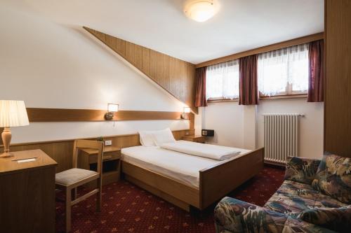阿拉巴Laguscei Dolomites Mountain Hotel的配有一张床和一把椅子的酒店客房