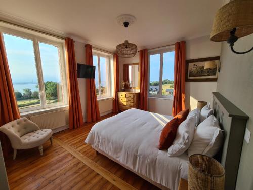 翁弗勒尔La Terrasse de l'Estuaire - Honfleur的一间卧室配有橙色窗帘和一张带椅子的床
