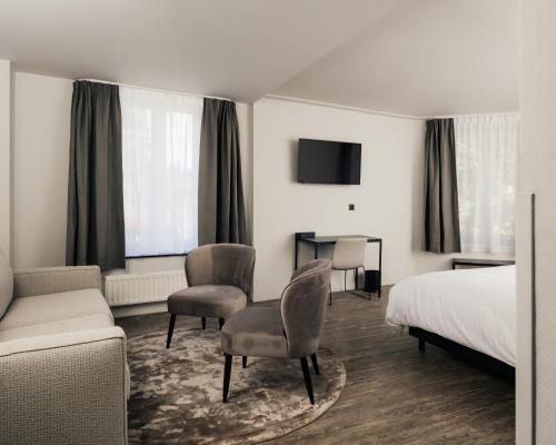 莱斯河畔的汉恩Hotel Au lit des ours的酒店客房配有一张床、一张沙发和椅子。