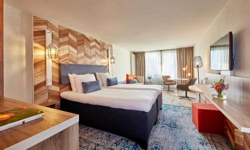 斯海弗宁恩卡尔顿海滩的配有一张床和一张书桌的酒店客房