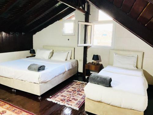 ŞahinbeyDostlar Konagi的一间卧室配有两张床和一张桌子,铺有地毯。