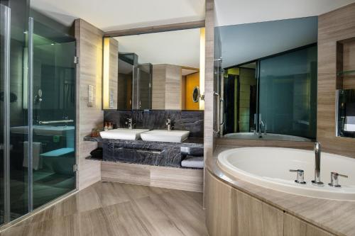 龙岗深圳龙岗珠江皇冠假日酒店的浴室配有2个盥洗盆和1个浴缸。