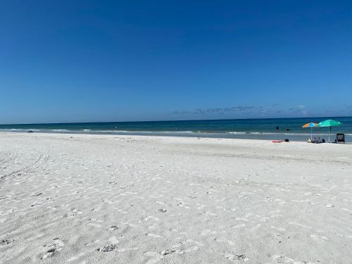 克利尔沃特Belleview Gulf Condos的沙滩上,有两把遮阳伞和大海