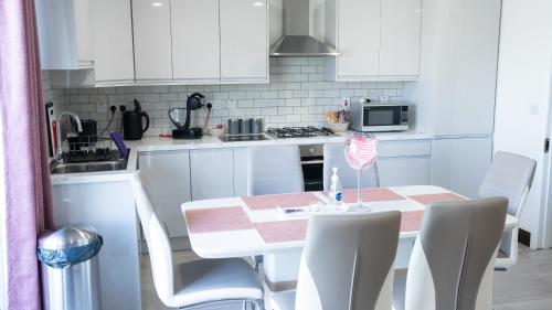 多尼戈尔Doonan Breeze的厨房配有白色橱柜和桌椅