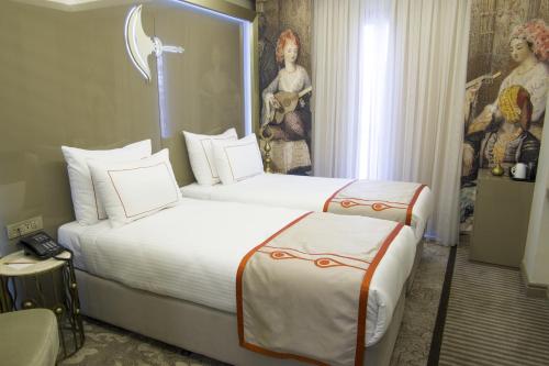 伊斯坦布尔佩科酒店的酒店客房设有两张床,墙上挂有绘画作品