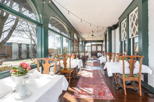 温斯顿·塞勒姆The Shaffner Inn的餐厅设有白色的桌椅和窗户。