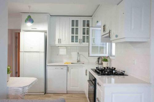 达特恰Mor Salkım Evi的白色的厨房配有炉灶和白色橱柜。