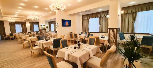克兰内沃ApartHotel Olympus Plaza的餐厅设有白色的桌椅和窗户。