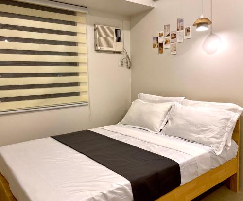大雅台Nordic Bleu Staycation at Ayala Serin的一间卧室配有一张带白色床单的床和一扇窗户。