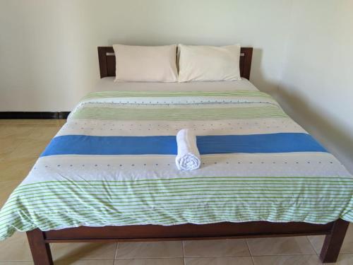 克里穆图ANDY'S LODGE KELIMUTU的一张带蓝色和绿色床单及白色枕头的床