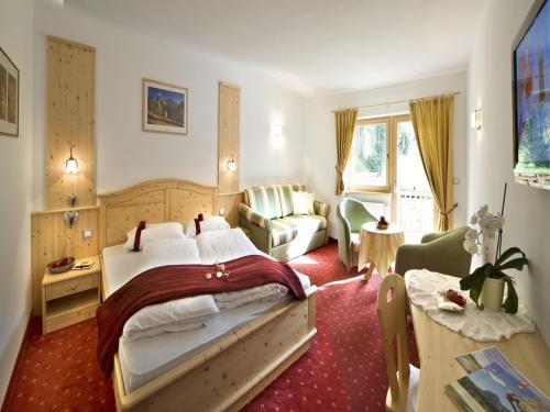塞尔瓦迪加尔代纳山谷Hotel Florian的一间卧室配有一张床、一张沙发和一张桌子