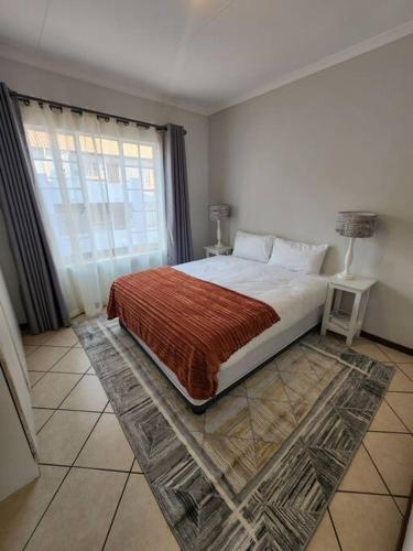 逊邱伦Elegant 2 bed apartment next to Gautrain Centurion的一间卧室设有一张大床和一个窗户。