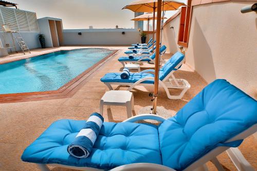 迪拜阿尔巴沙招牌酒店的游泳池旁的游泳池,泳池旁摆放着一束蓝色的椅子