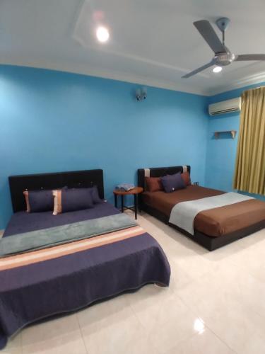阿罗士打Homestay Banglo Alor Setar的一间卧室设有两张床和蓝色的墙壁