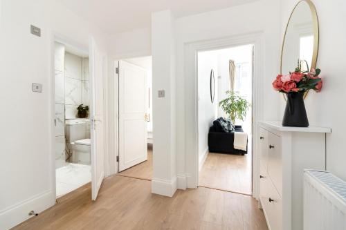 伦敦Majestic Luxury Apartment in Marylebone的白色的浴室,配有镜子和花瓶