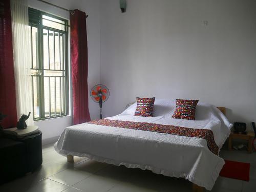 基加利Villa Kikiriki的卧室配有带枕头的白色床和窗户。