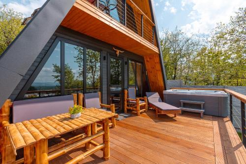 姆茨赫塔Modern Wood Cottages的房屋设有带热水浴池和桌子的甲板